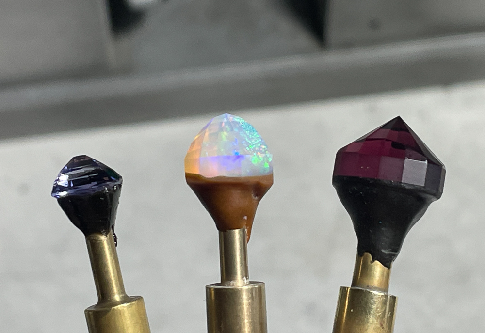 three gemstones on dop in process of cutting